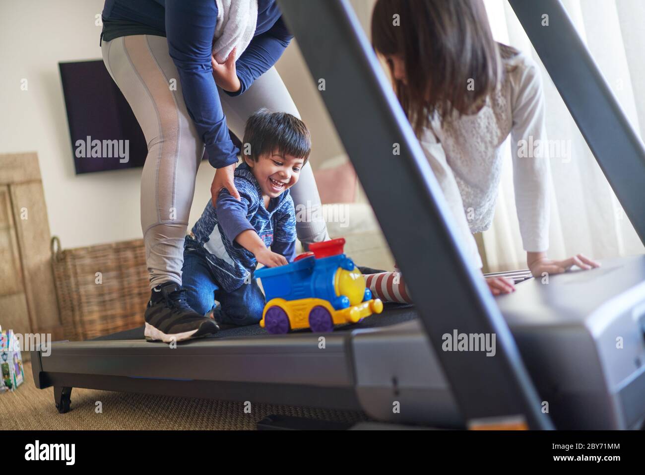 Happy mother and kids with toys on treadmill Stock Photo