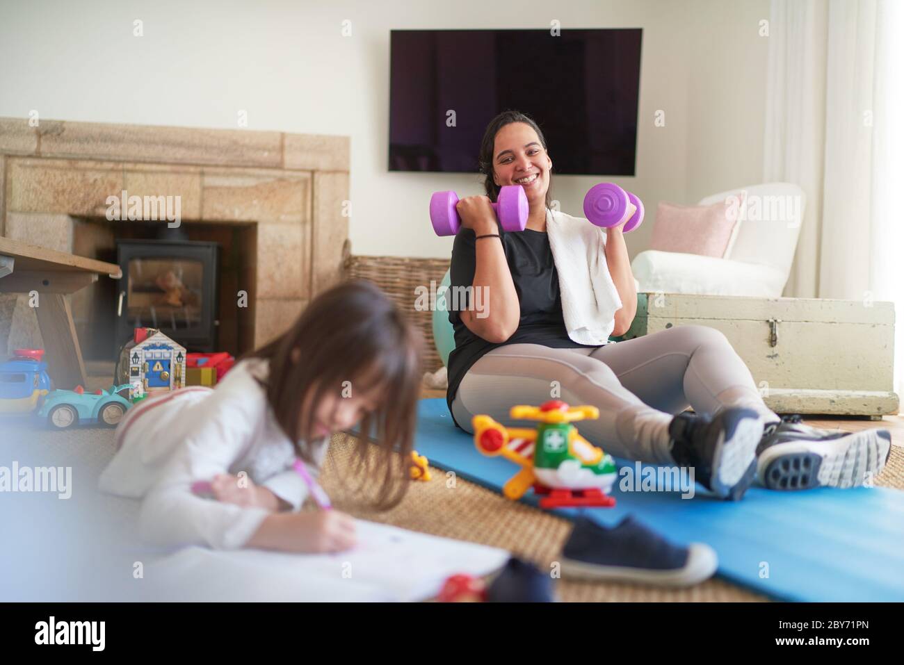 Happy mother exercising and watching daughter drawing Stock Photo