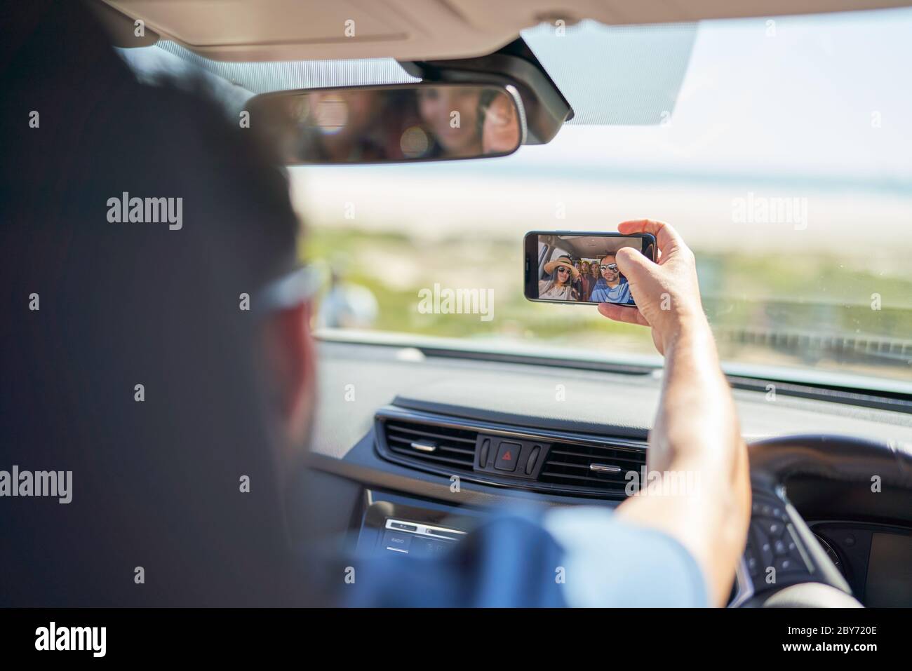 Family on road trip taking selfie with camera phone in sunny car Stock Photo