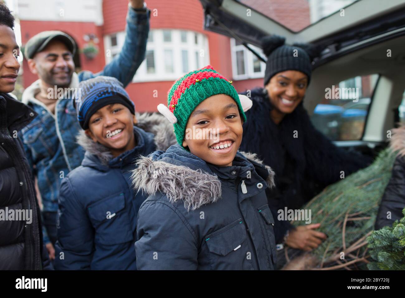 Portrait happy family loading Christmas tree in car Stock Photo