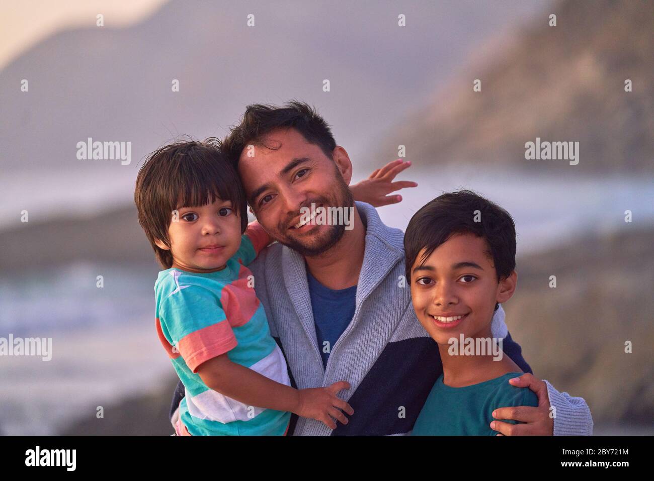 Portrait happy father and sons on beach Stock Photo