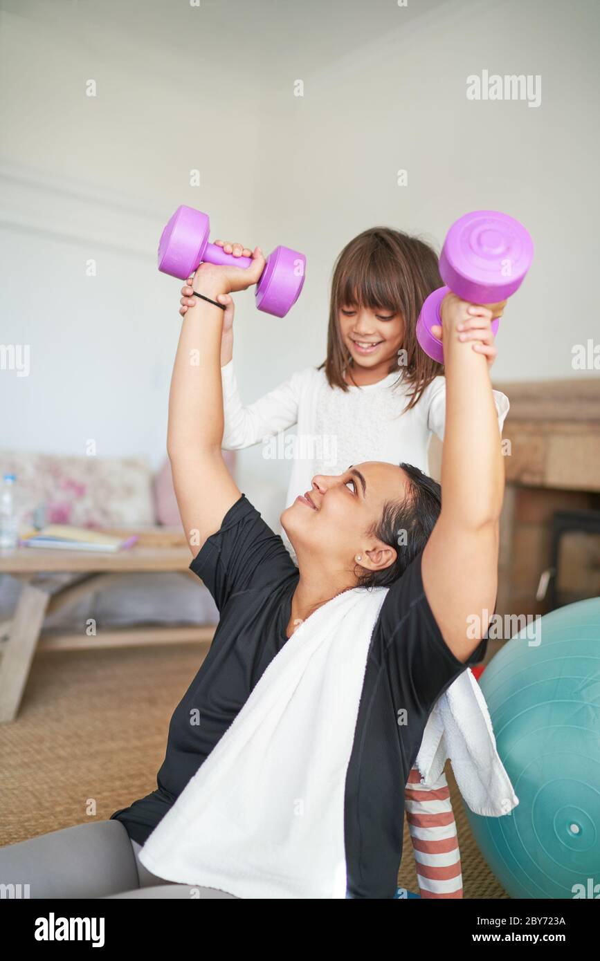 Daughter helping mother exercising with dumbbells Stock Photo
