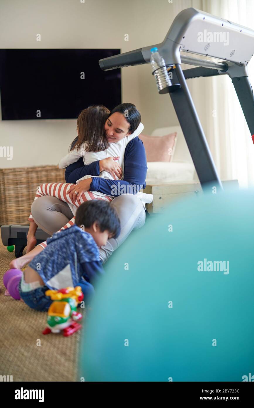 Affectionate mother and daughter hugging in living room Stock Photo