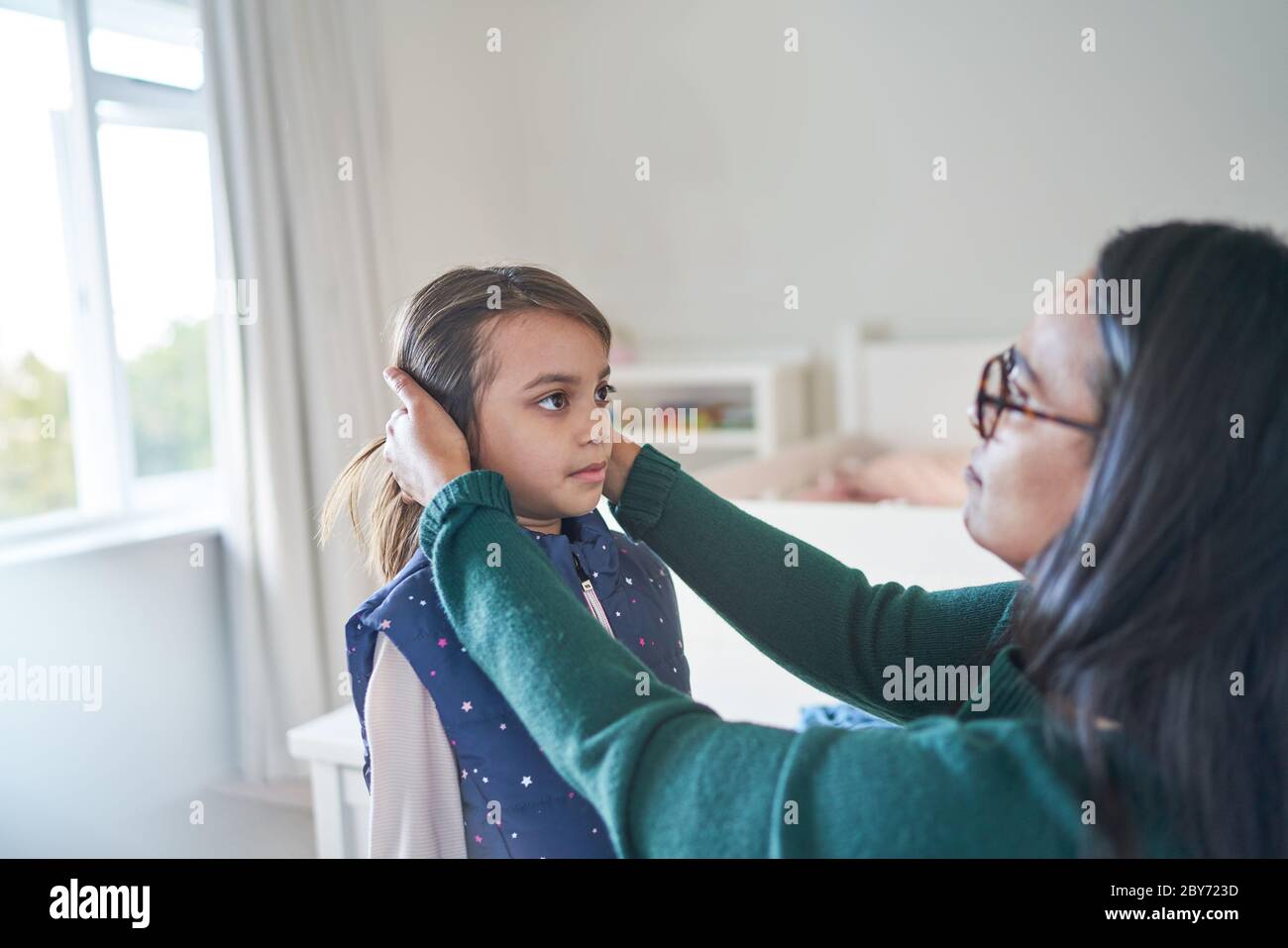Mother helping daughter fix hair Stock Photo