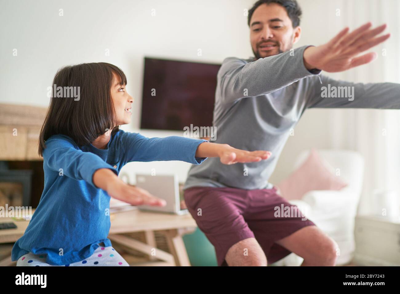 Father and daughter exercising doing squats in living room Stock Photo