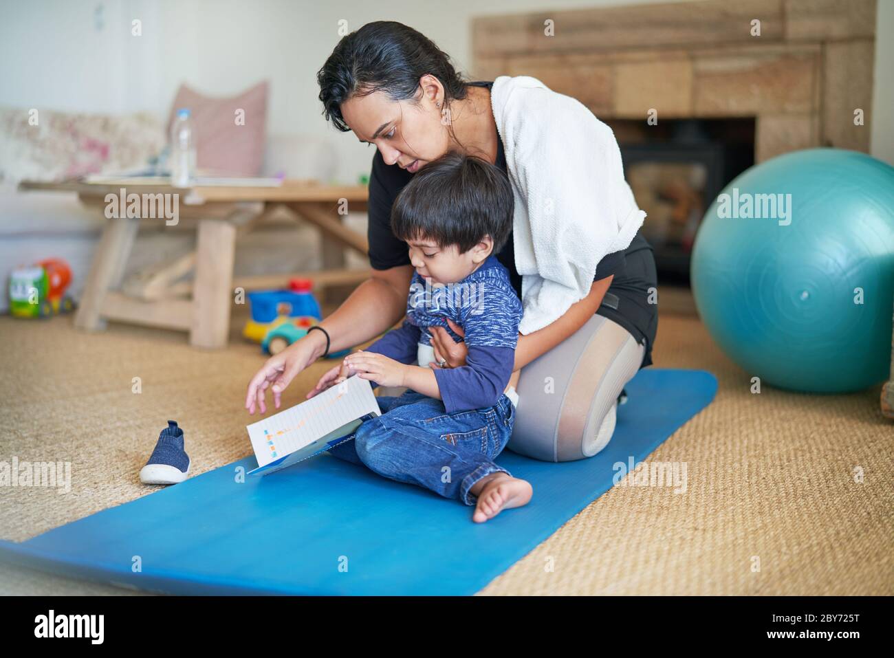 Mother and son on yoga mat in living room Stock Photo