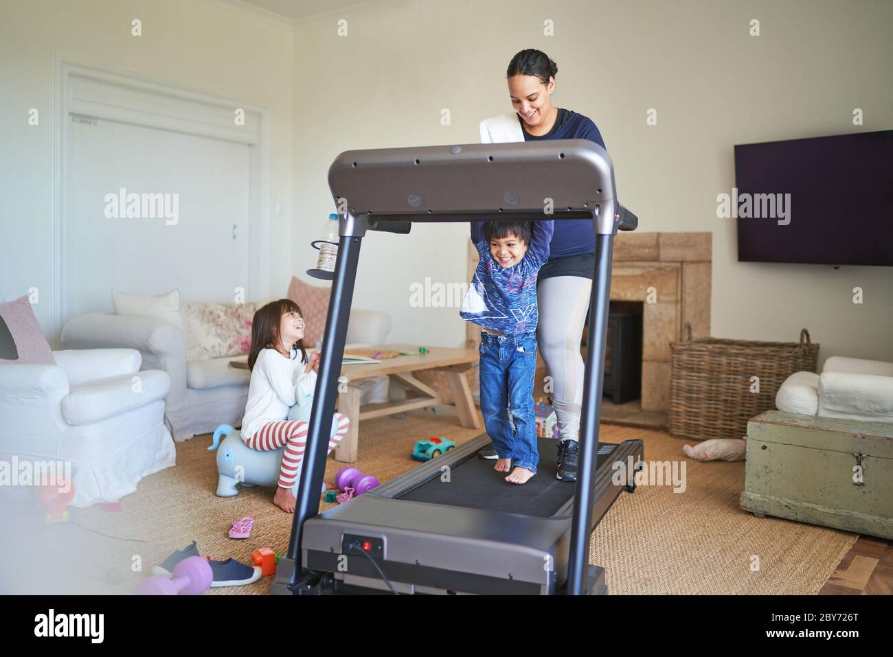 Mother and son walking on treadmill in living room Stock Photo