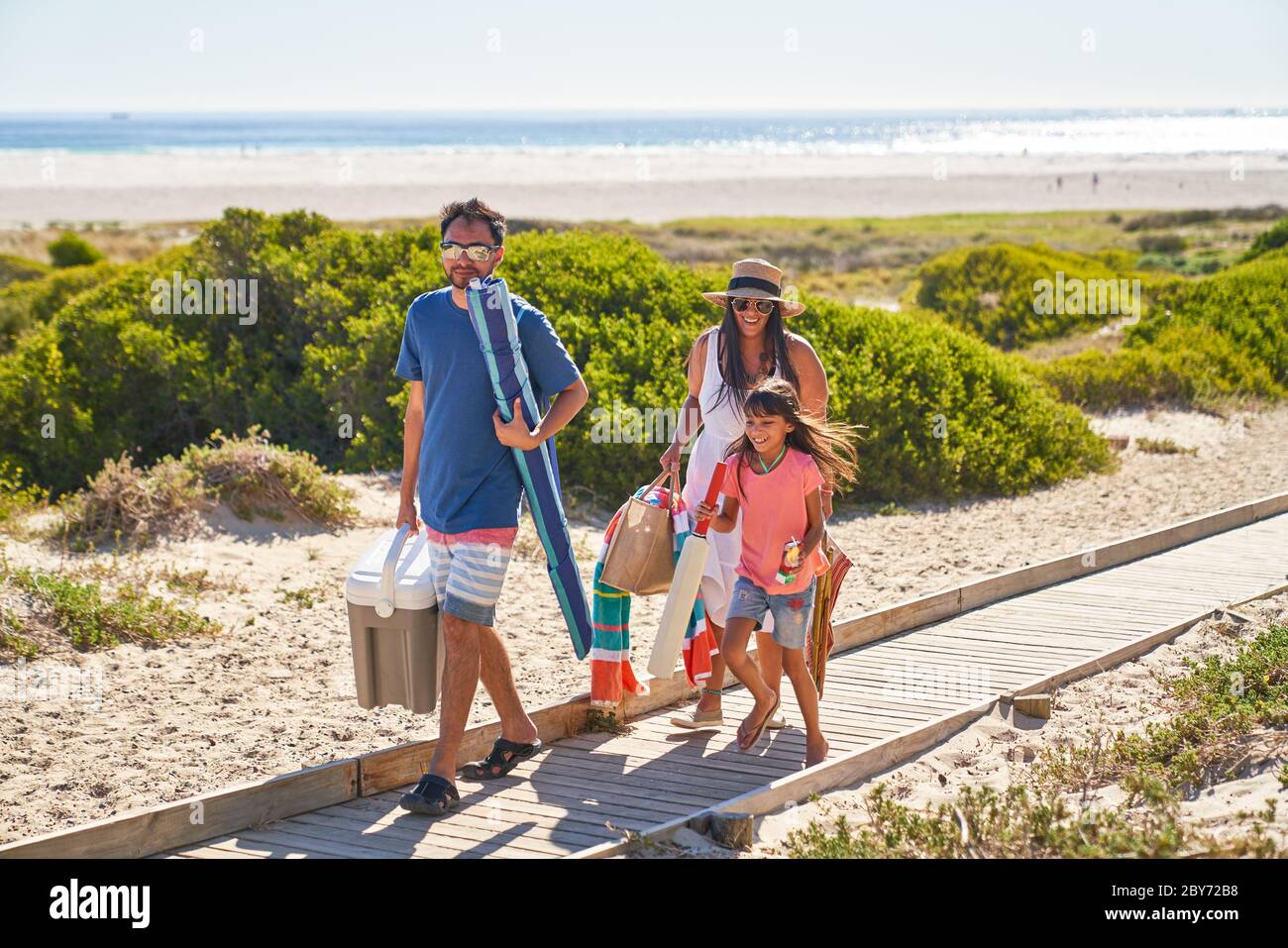 Happy family walking on sunny beach boardwalk Stock Photo