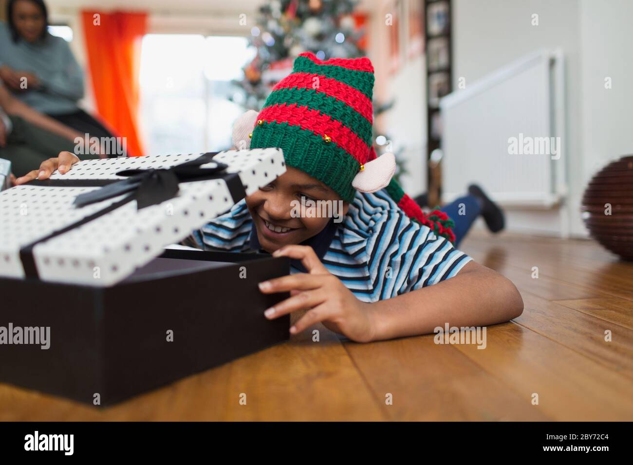 Excited boy opening Christmas gift on living room floor Stock Photo