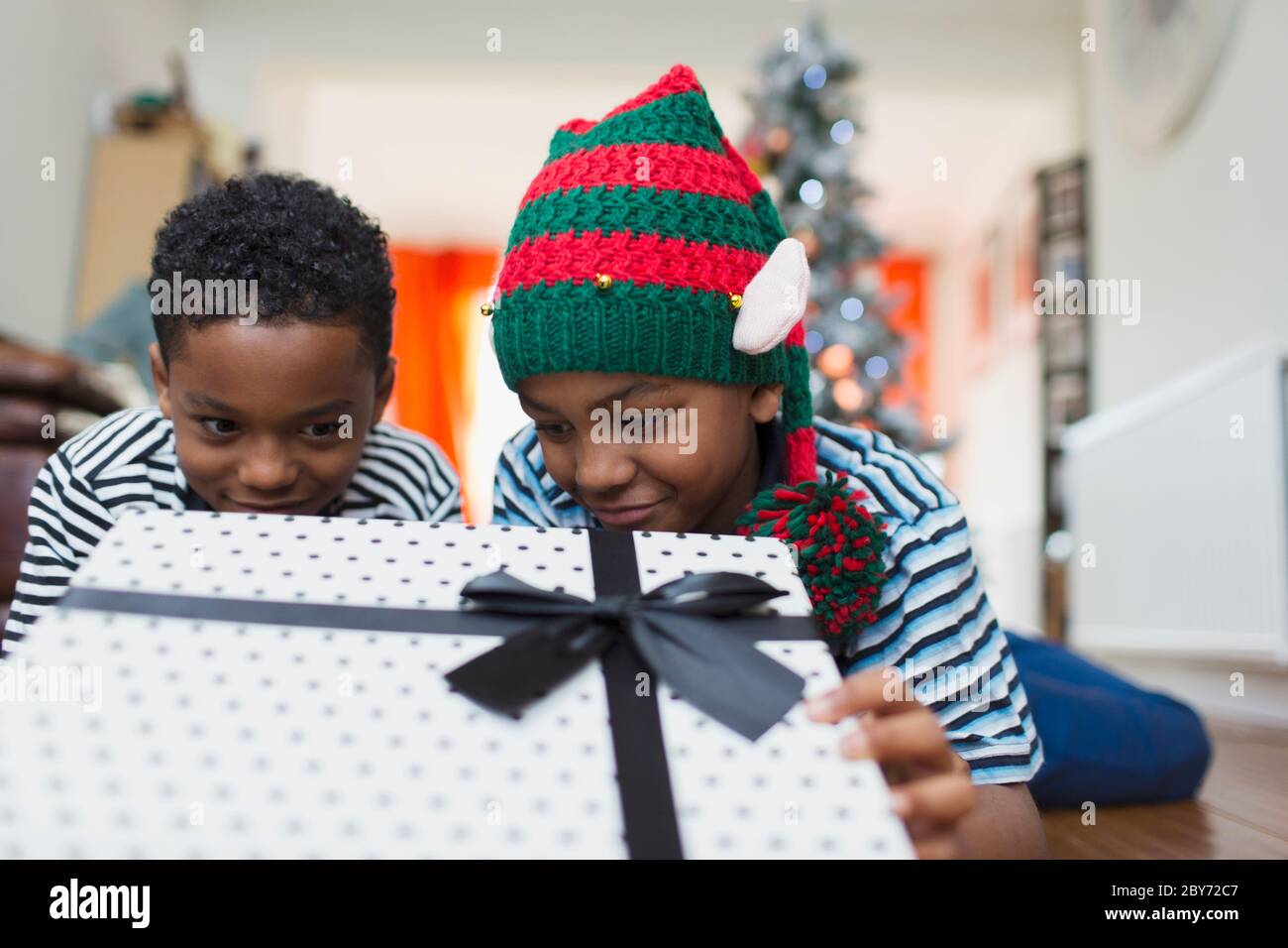 Curious brothers peeking at Christmas gift Stock Photo