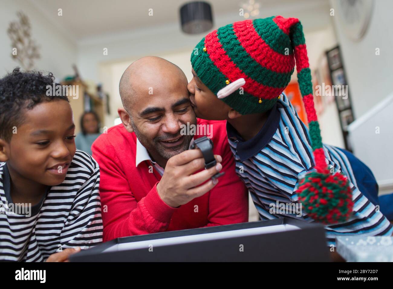 Happy son kissing father opening Christmas gift Stock Photo