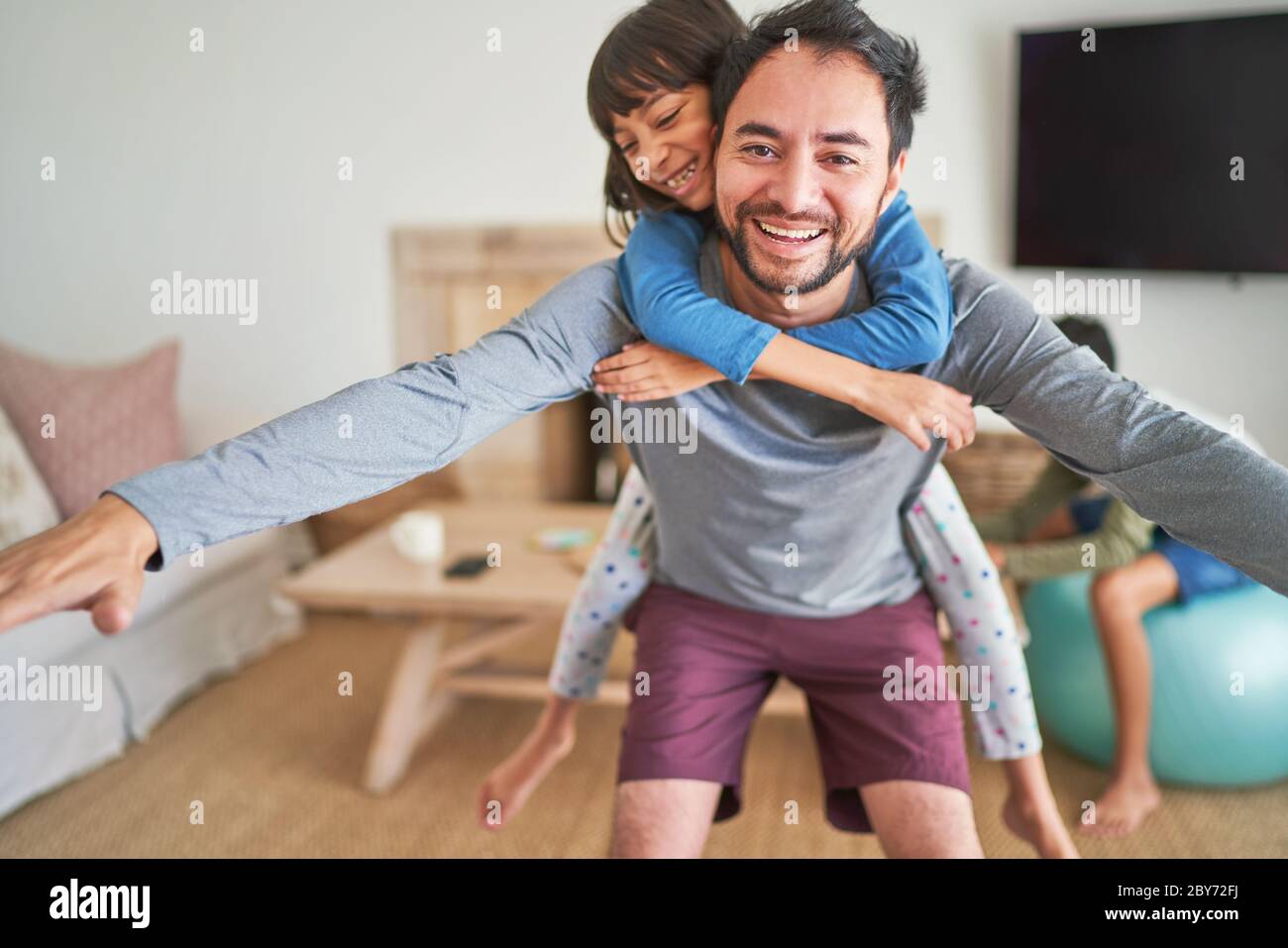 Portrait playful father piggybacking daughter Stock Photo