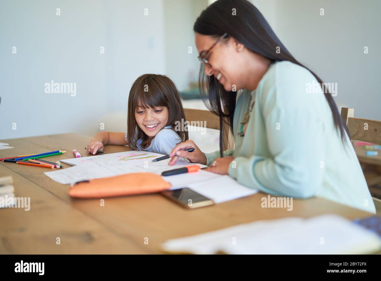Mother helping daughter with homework at table Stock Photo - Alamy