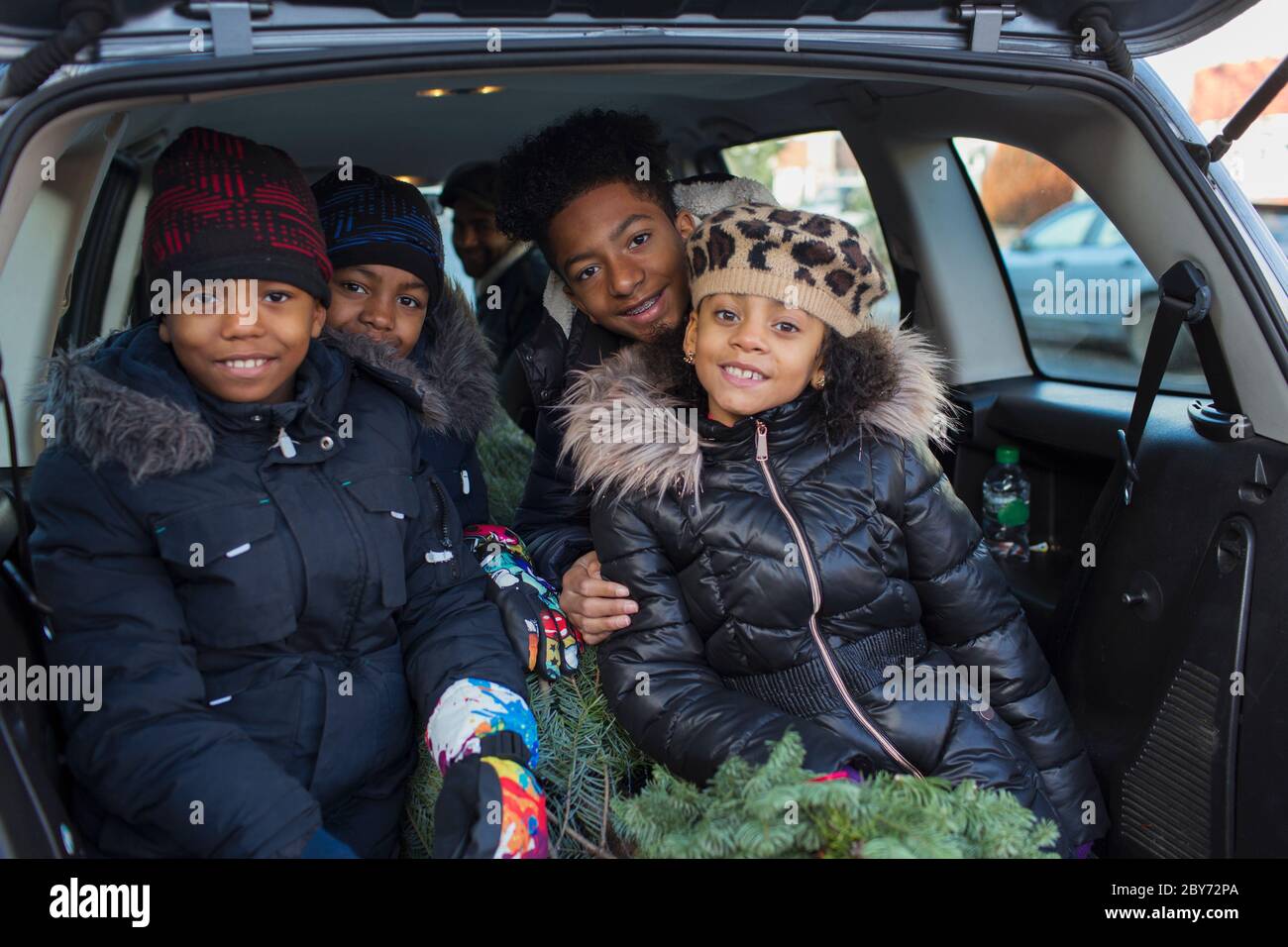Portrait happy brothers and sister with Christmas tree in back of car Stock Photo