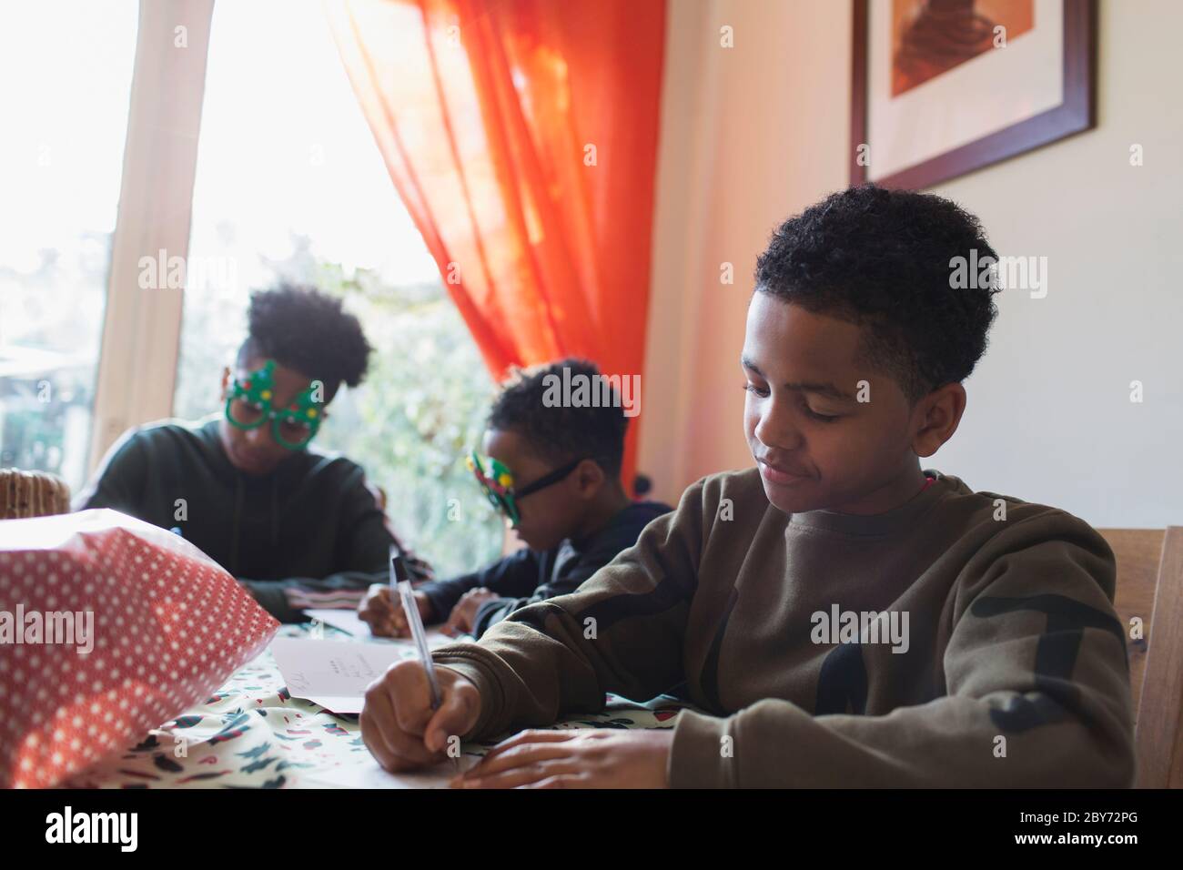 Boy writing Christmas cards at table Stock Photo