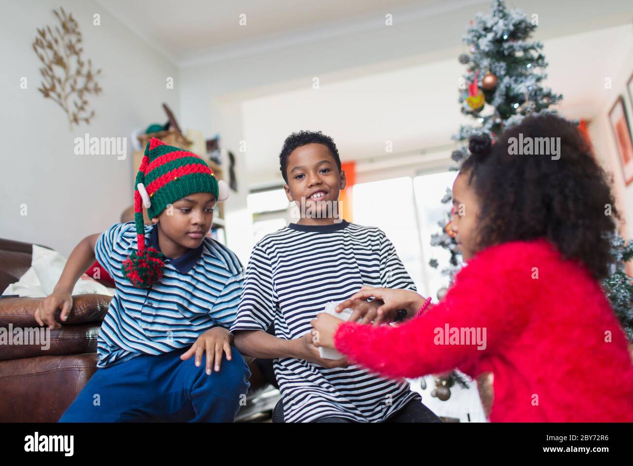 Brothers and sister opening Christmas gifts in living room Stock Photo