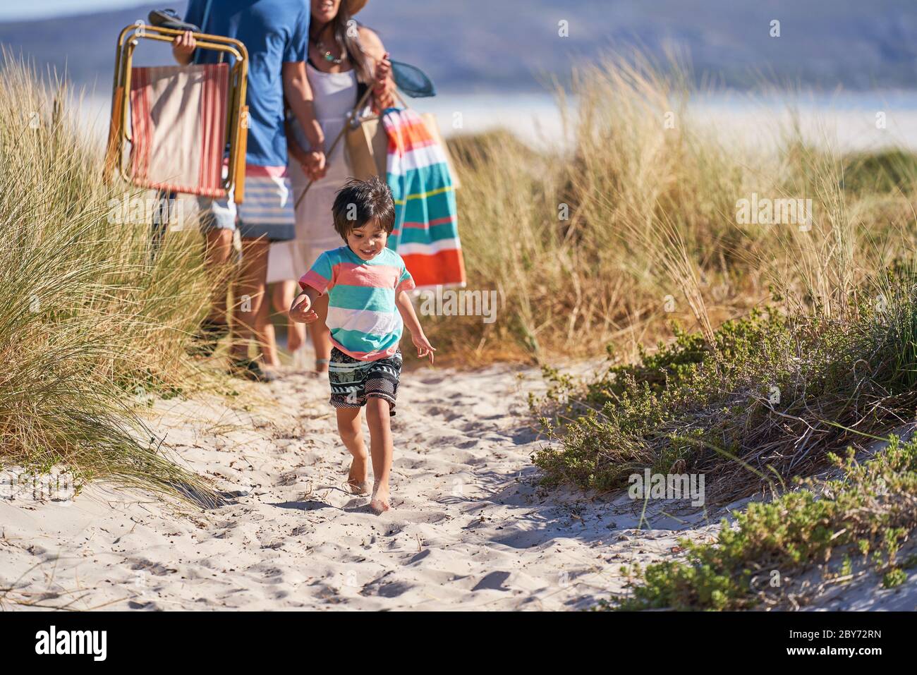 Happy boy walking on sunny beach path Stock Photo