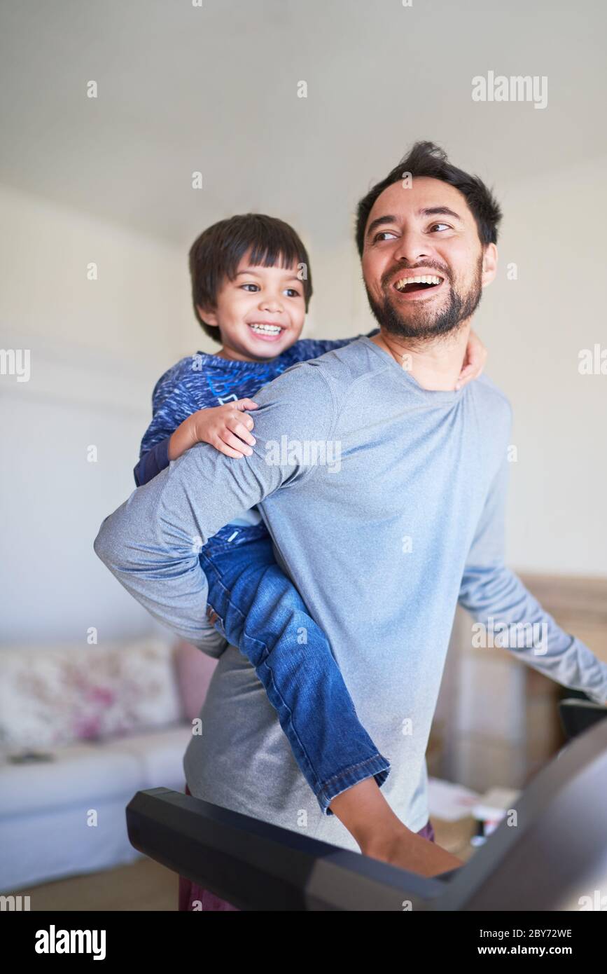 Happy father piggybacking son on treadmill Stock Photo