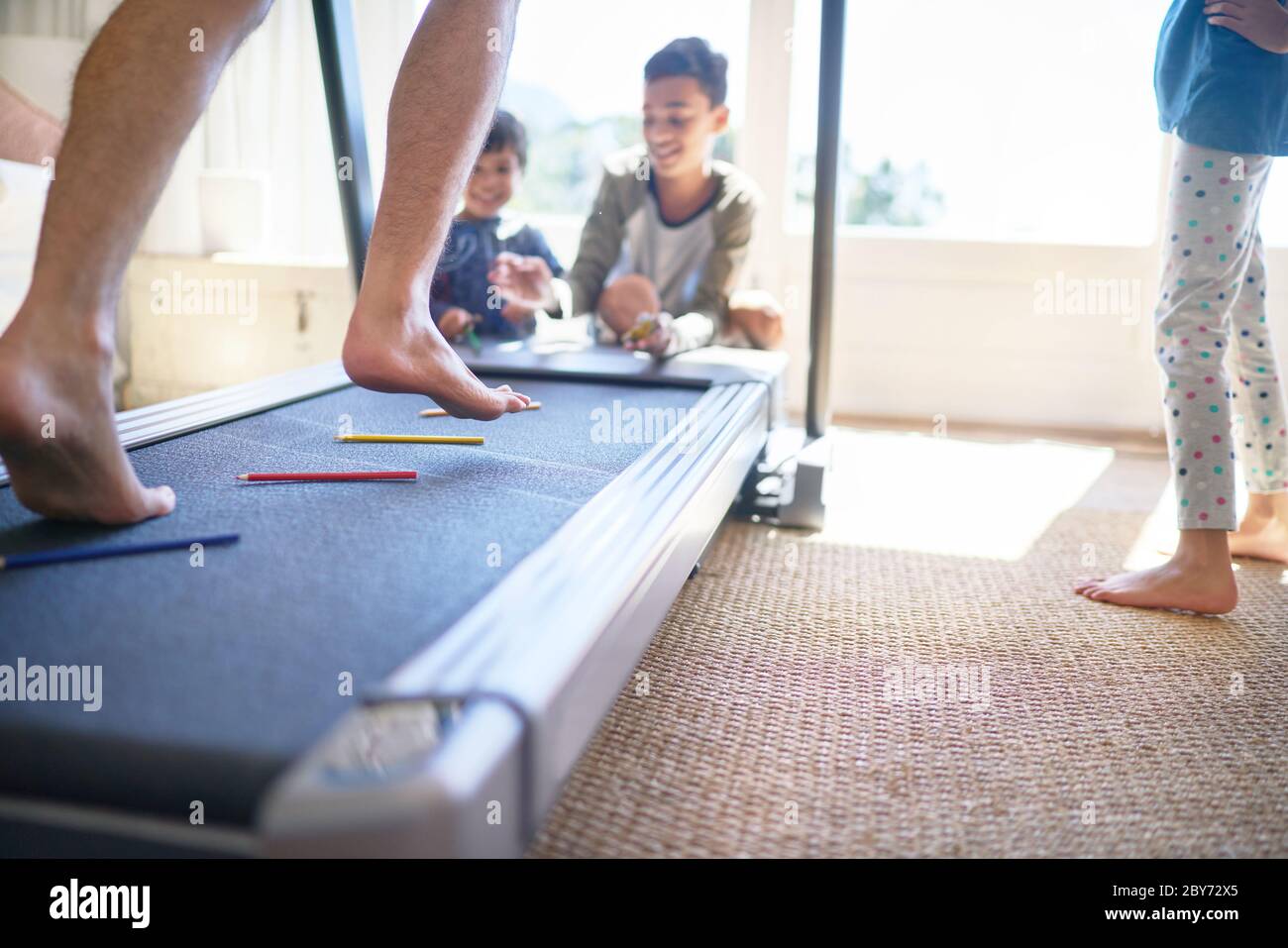Kids throwing colored pencils on treadmill with father jogging Stock Photo