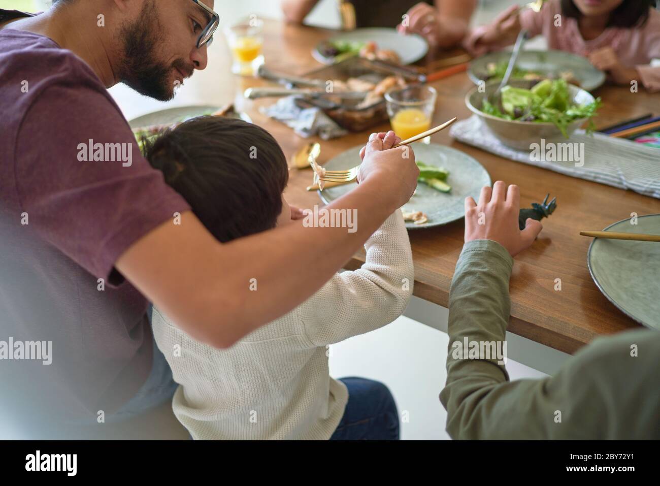 Father feeding toddler son at dinner table Stock Photo