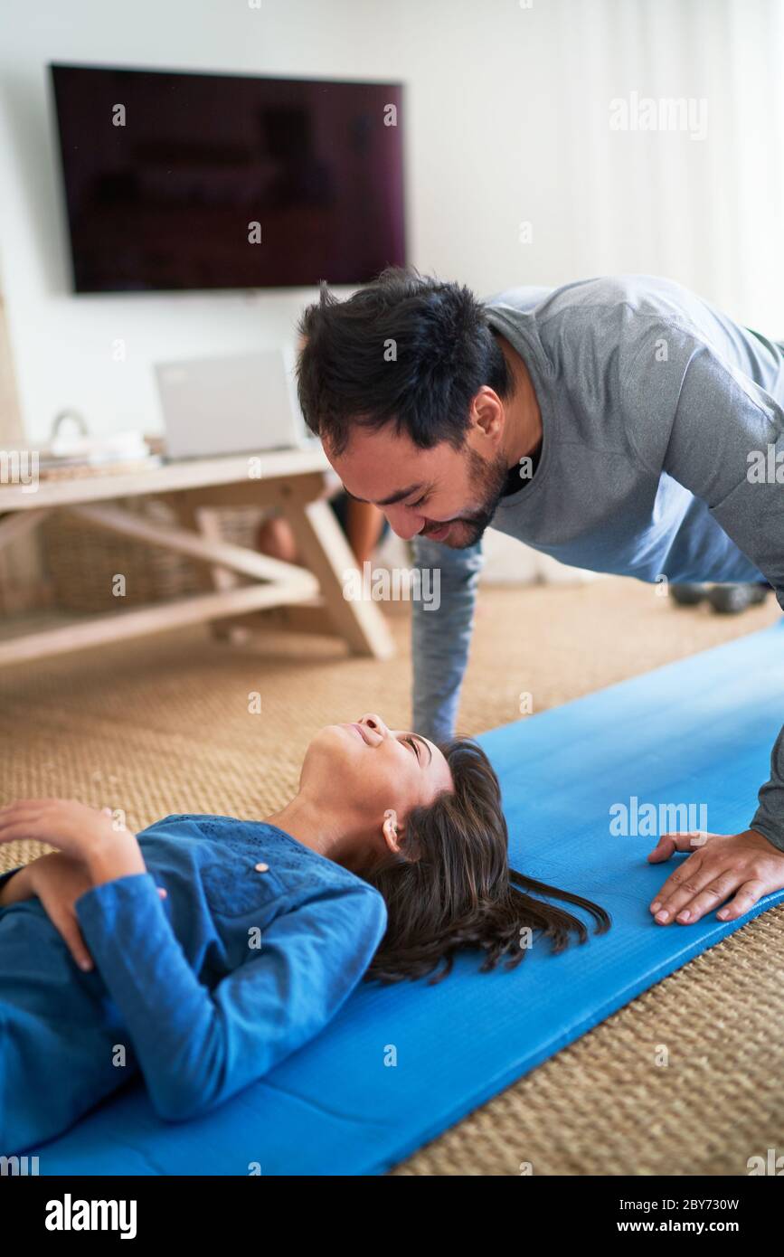 Playful father and daughter exercising in living room Stock Photo