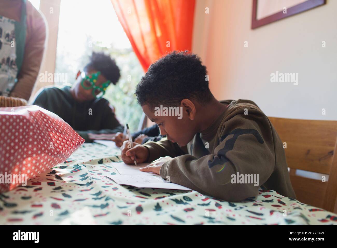 Boy writing Christmas cards at table Stock Photo
