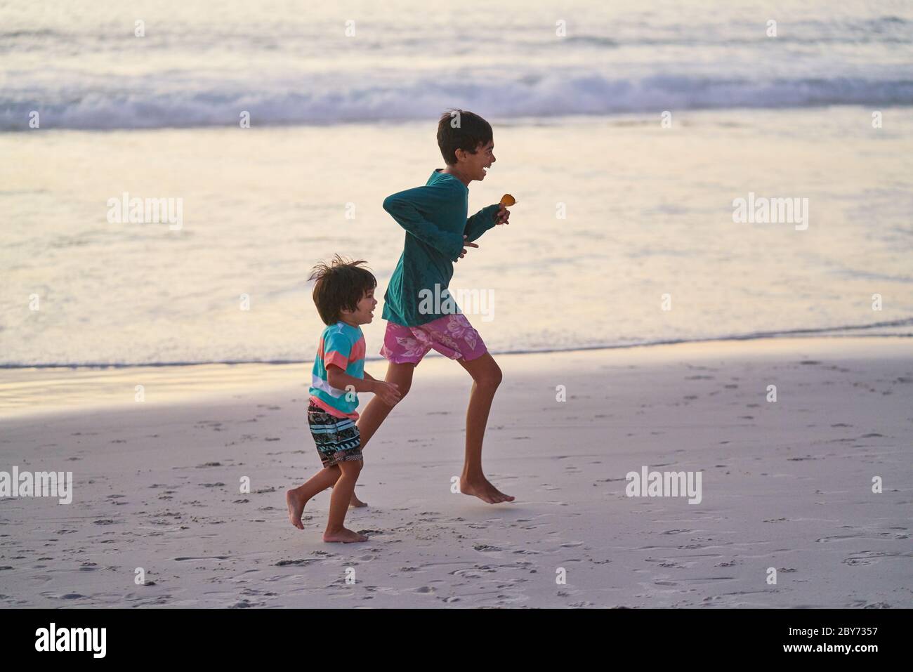 Happy brothers running on ocean beach Stock Photo