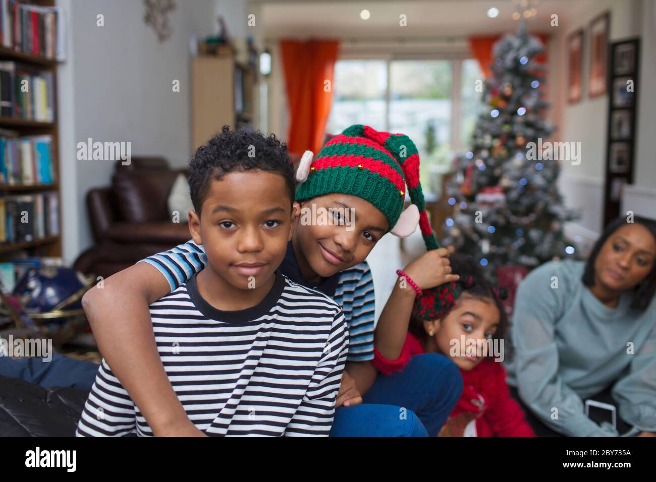 Portrait happy brothers hugging in Christmas living room Stock Photo