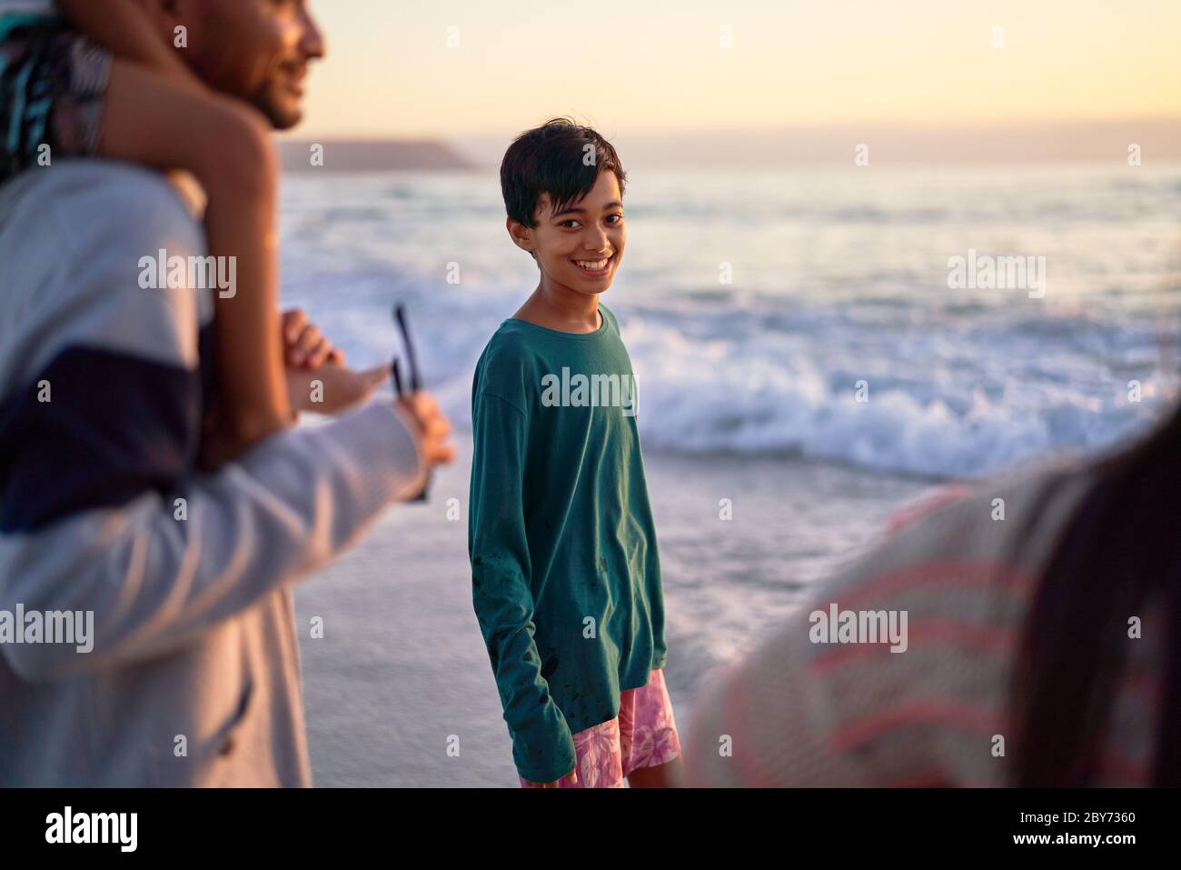 Portrait happy boy on ocean beach with family Stock Photo