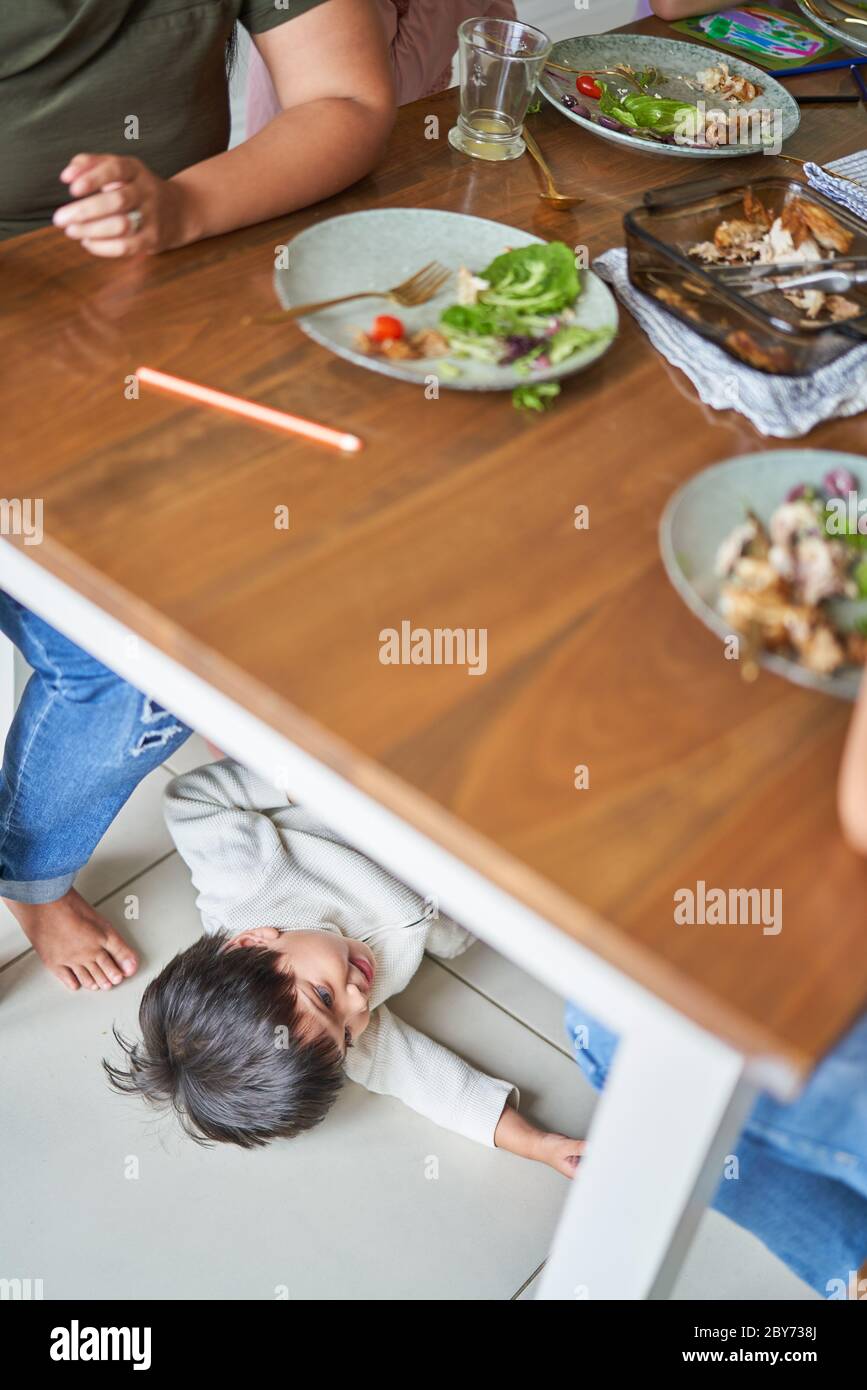 Boy playing under dinner table Stock Photo