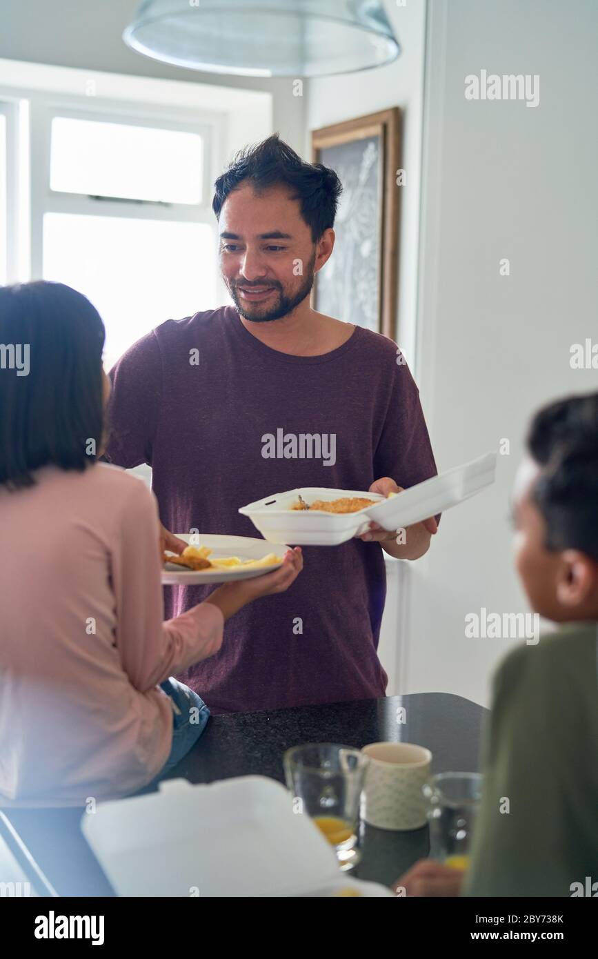 Father and kids eating takeout food in kitchen Stock Photo