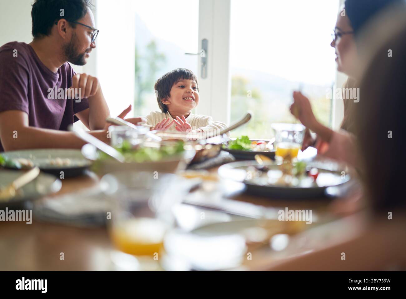 Happy family eating lunch at dining table Stock Photo