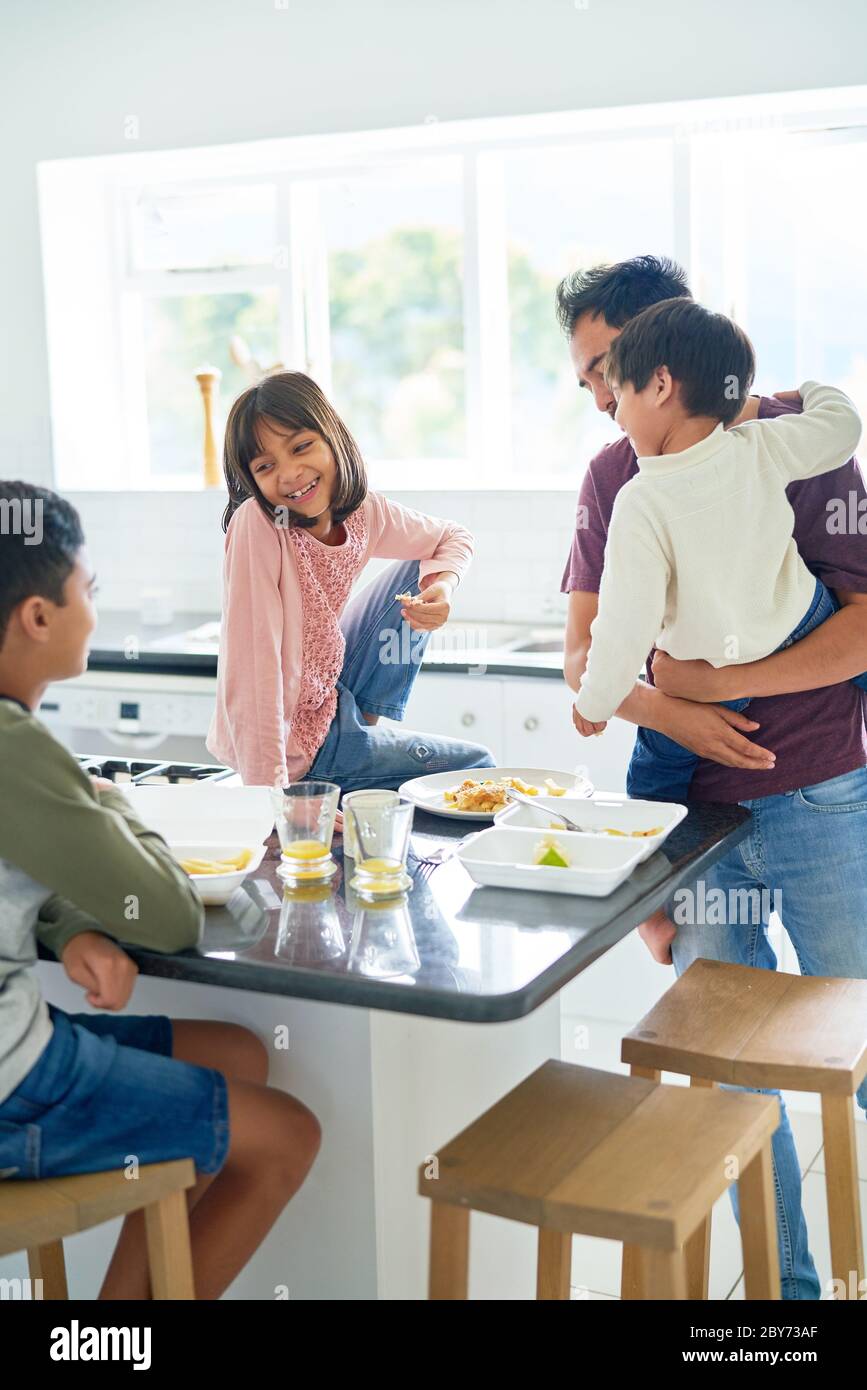 Father and kids eating takeout food in kitchen Stock Photo
