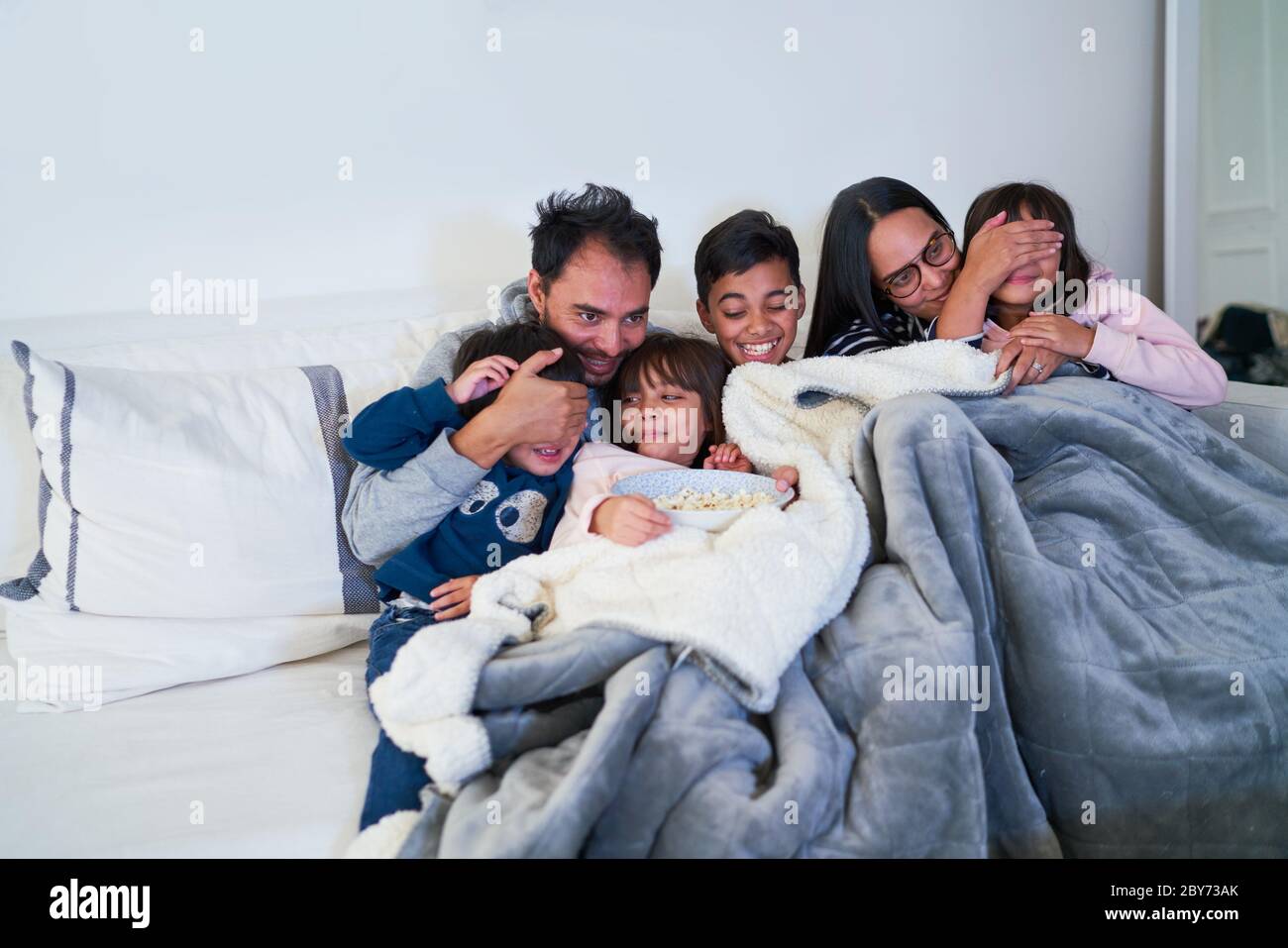 Happy family watching scary movie on living room sofa Stock Photo