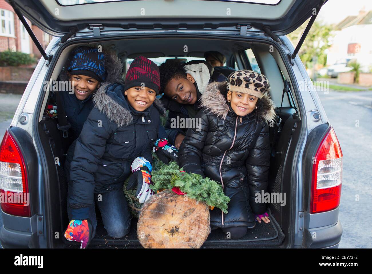 Portrait happy brothers and sister with Christmas tree in back of car Stock Photo