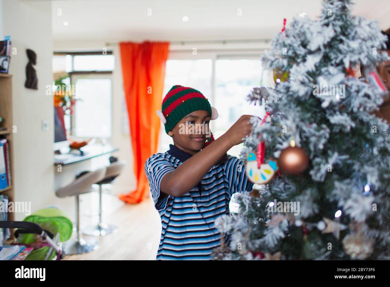 Boy decorating Christmas tree in living room Stock Photo