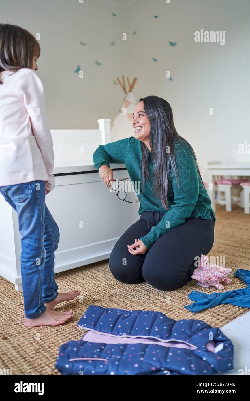 Happy mother and daughter doing laundry in bedroom Stock Photo