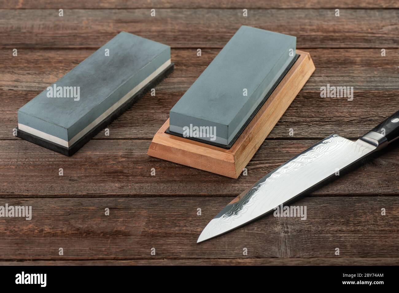 Man sharpening his pocket knife with a whetstone on a rustic wooden table  Stock Photo - Alamy