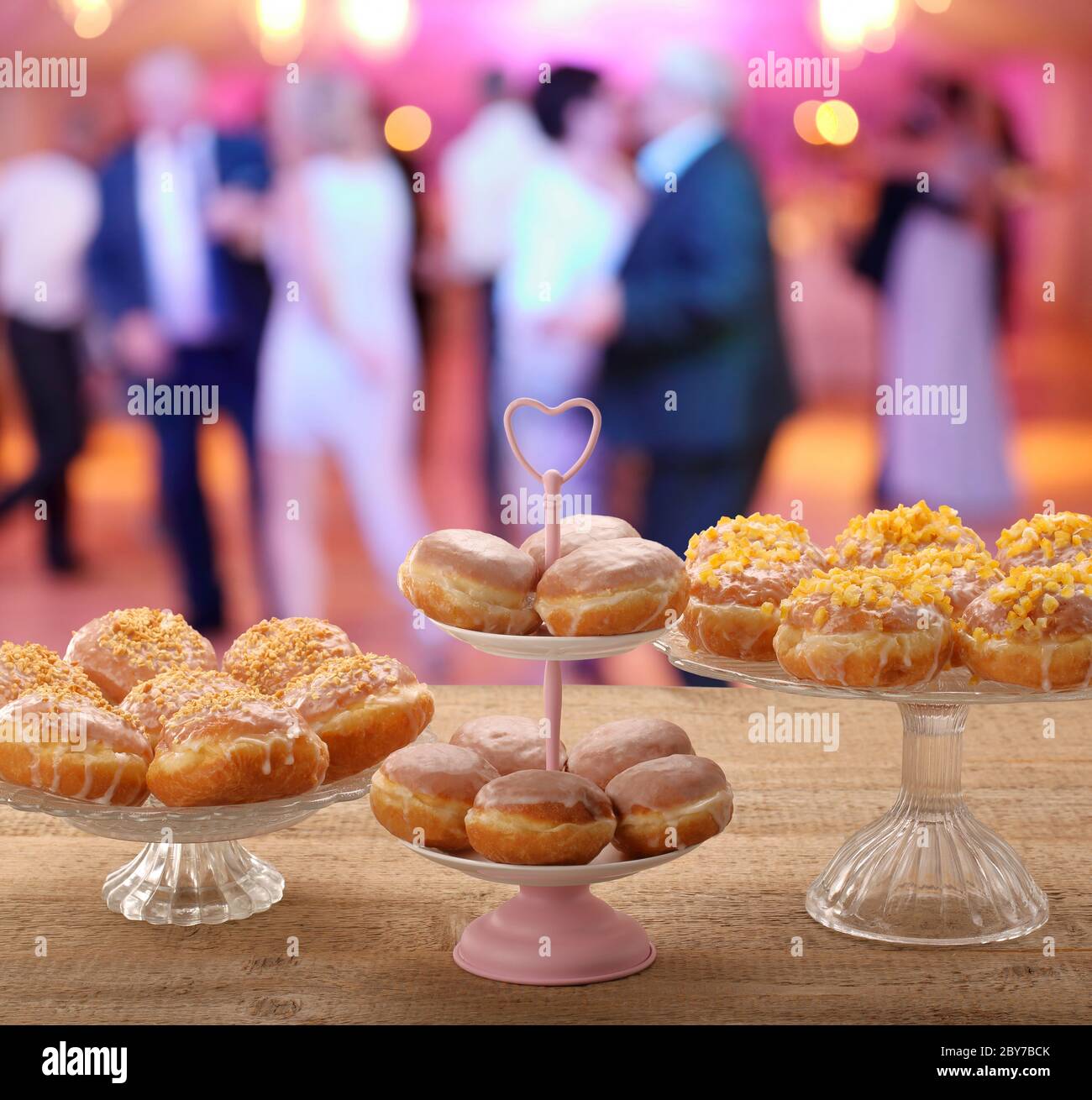 Fresh donuts on a plate and dancing people at the party in the background and empty space for text Stock Photo