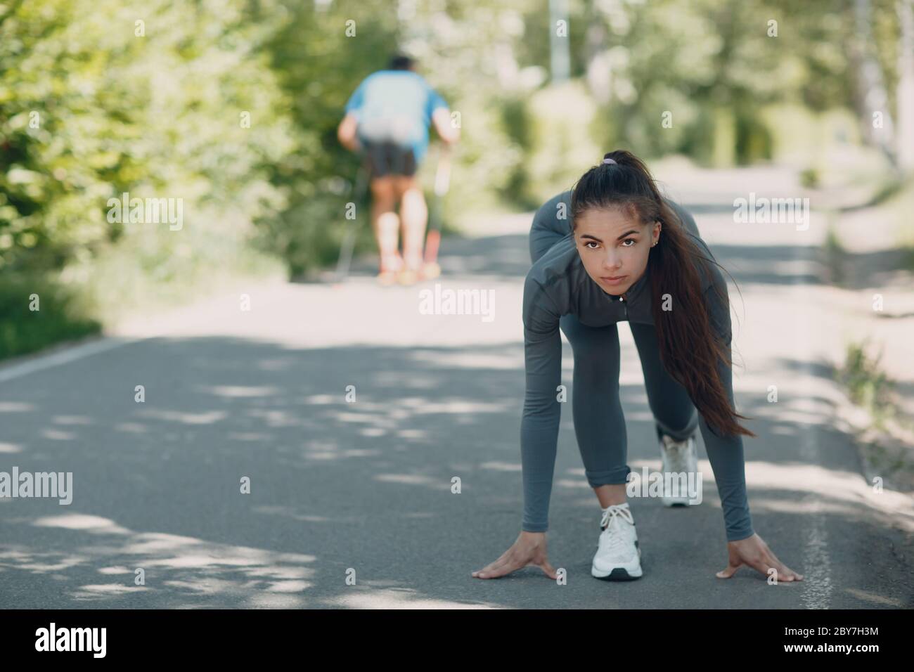 Running girl in city park. Young positive woman runner outdoor jogging. Stock Photo