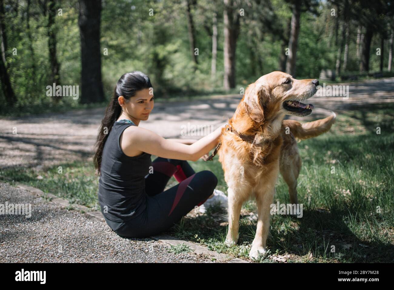 Young girl sitting on the ground in forest with her dog Stock Photo - Alamy