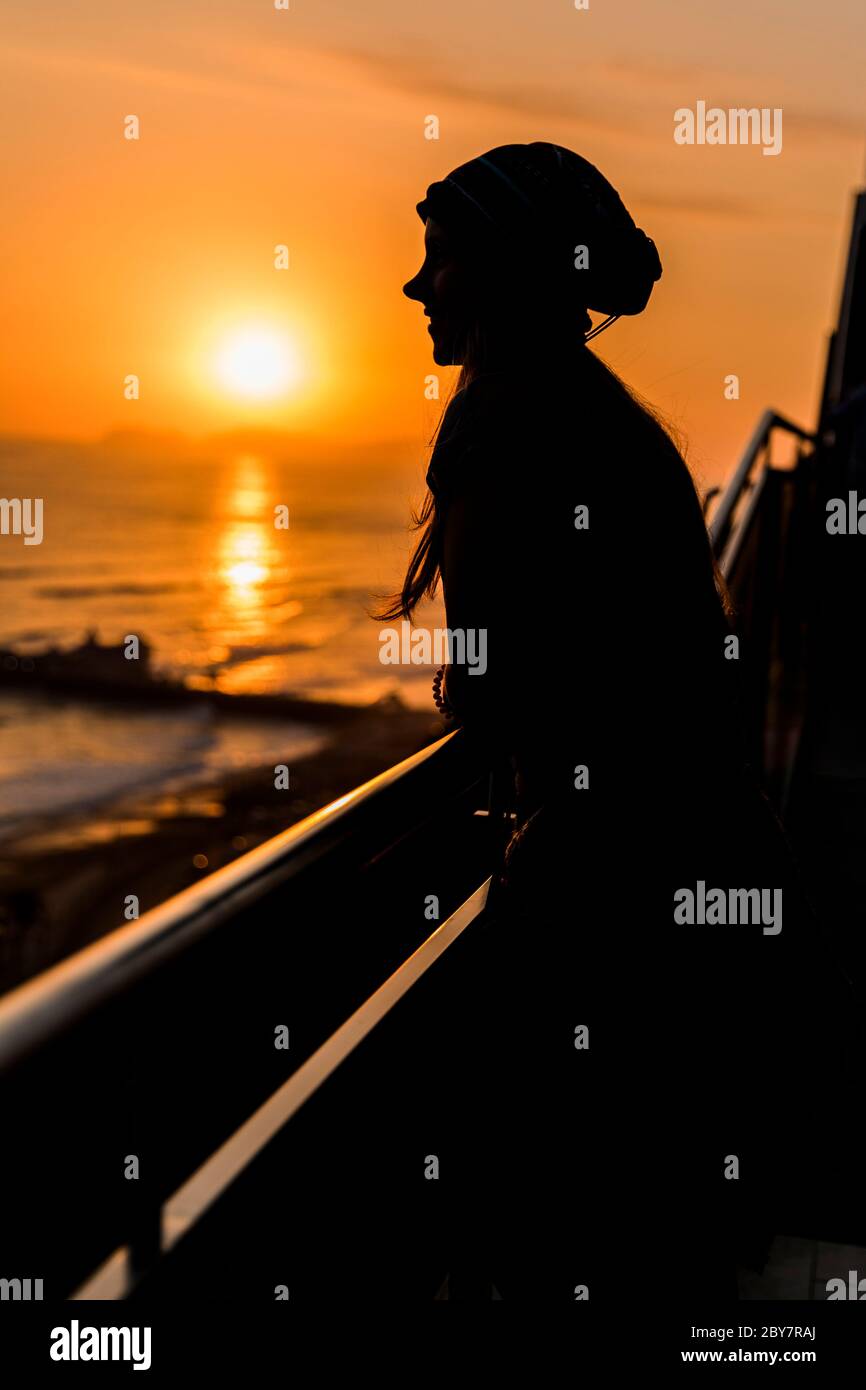 woman looking the sunset in a city with beach and a highway Stock Photo