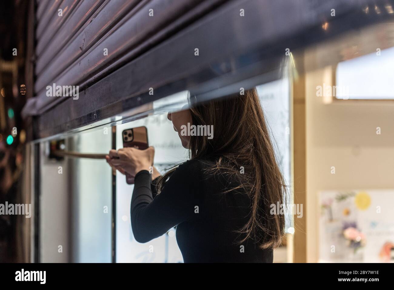 Hong Kong SAR, China. 9th June 2020. A worker closes the metal security door of her shop as hundreds of Hongkongers defy a police ban and take over the streets in the Central business district to mark the one year anniversary of the Hong Kong pro-democracy protests. Credit: Ben Marans/Alamy Live News. Stock Photo