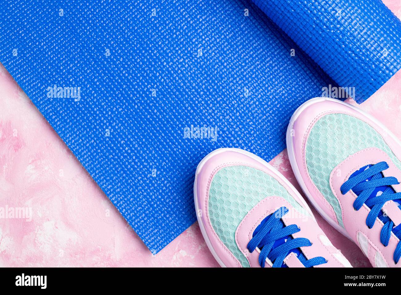 Blue yoga mat, sport shoes on pink background. Concept healthy lifestyle, sport life, fitness and diet. Sport equipment. Copy space Stock Photo