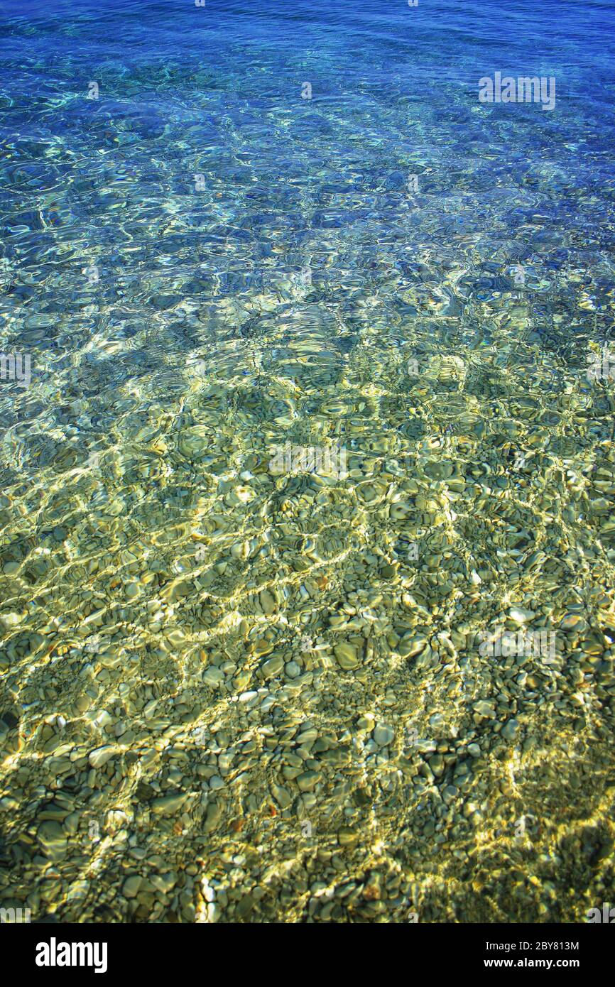 Beach pebbles under clear water with waves Stock Photo - Alamy