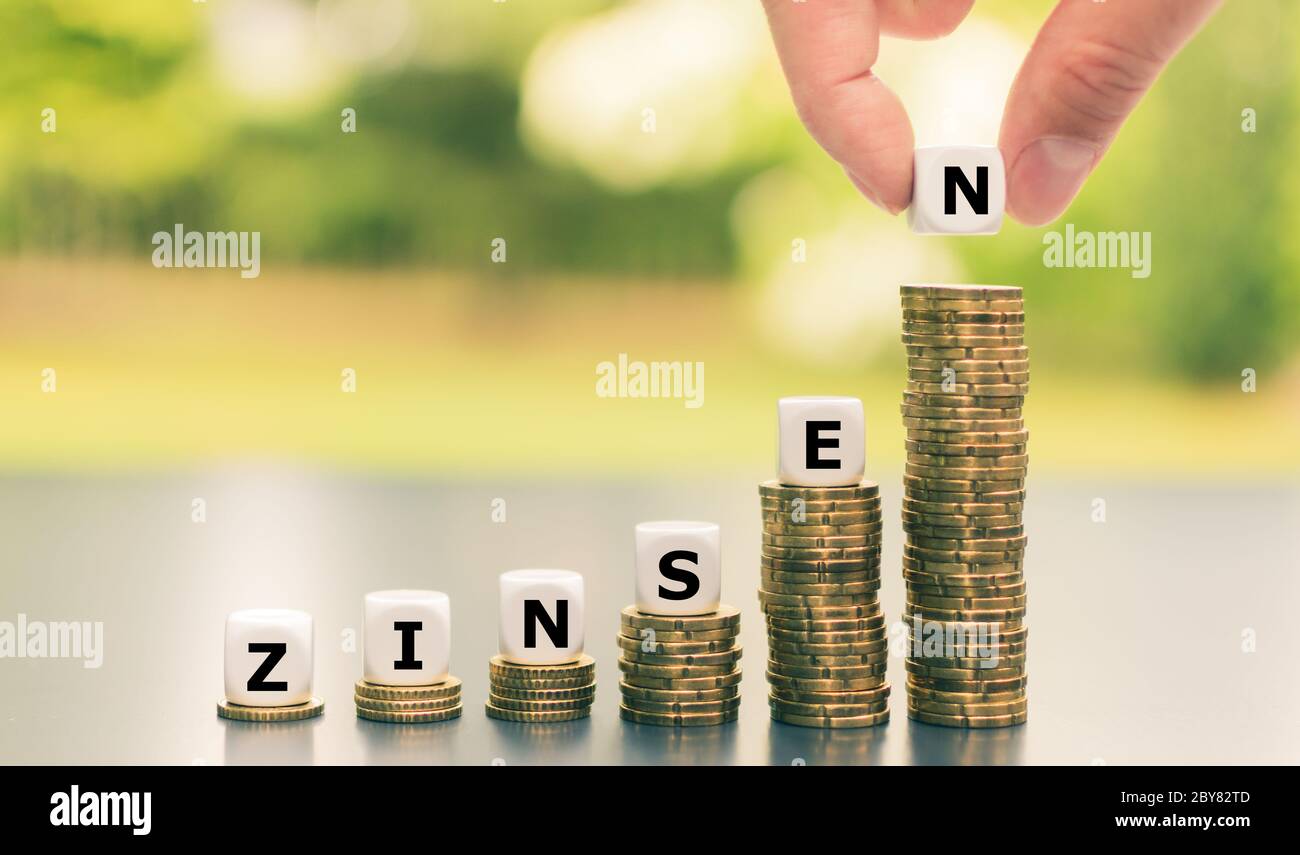 Dice form the German word 'Zinsen' ('interest rates') on increasing high stacks of coins. Stock Photo