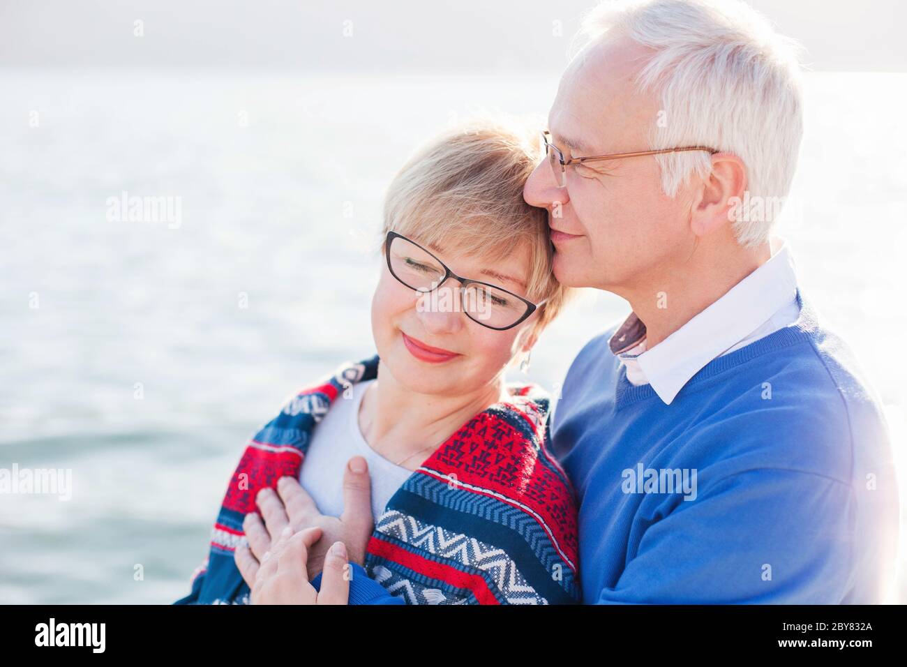 Senior couple is enjoying retirement and life at sea beach outdoor. Happy man and woman are hugging, embracing Stock Photo