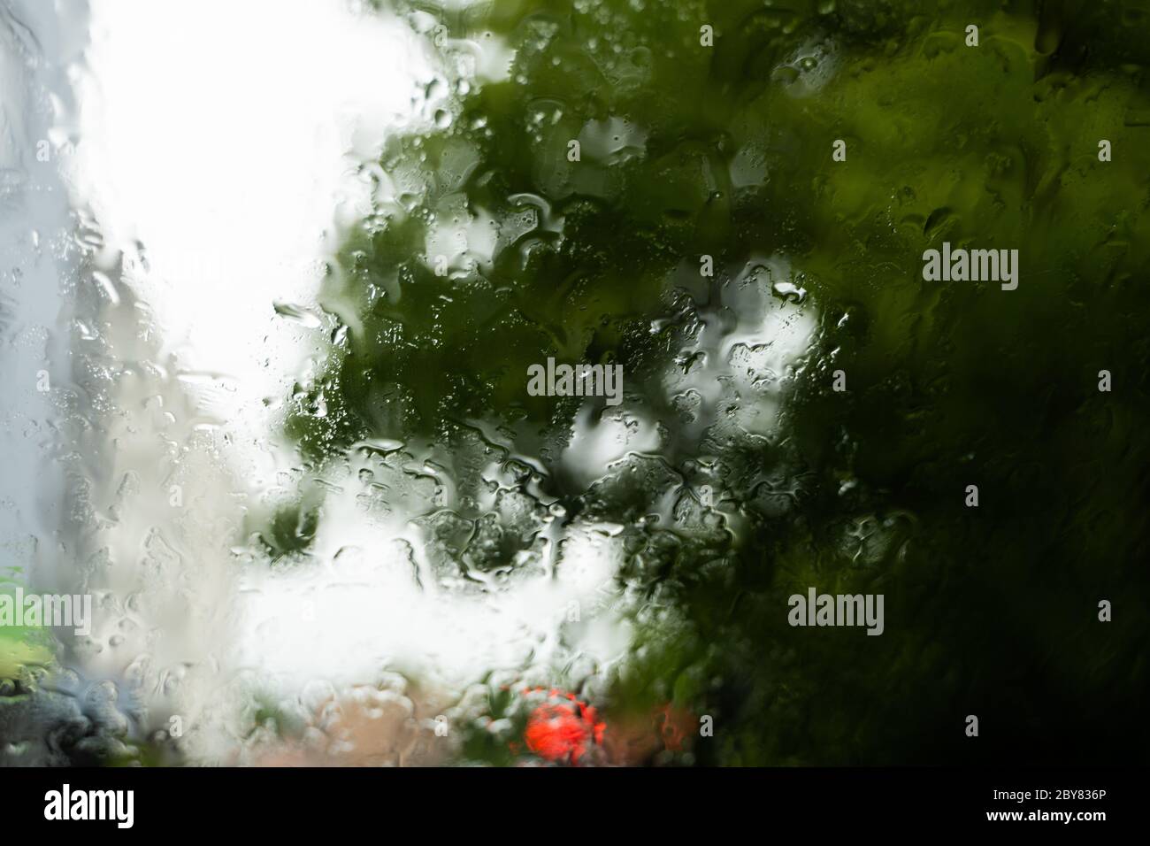 Raindrops on a windscreen glass with a blurred night city lights at the ...