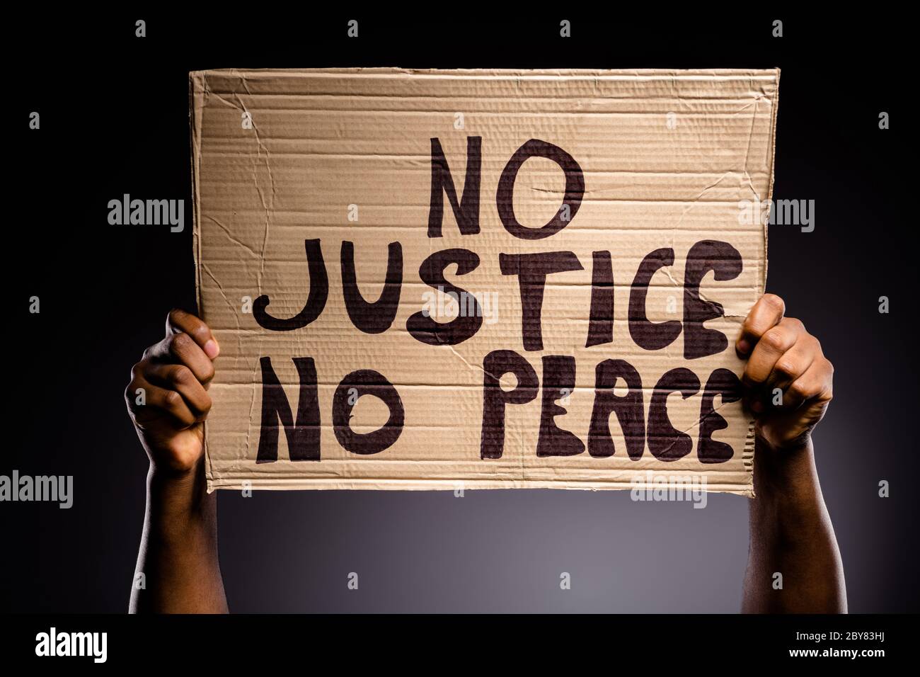Close up photo of afro american person hand hold cardboard banner with text no justice no peace continue fighting message isolated over black color Stock Photo