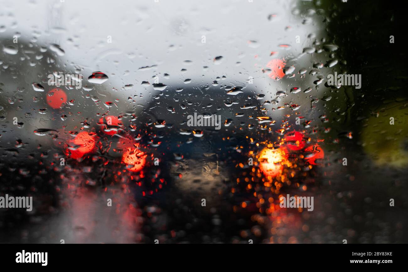 Raindrops on a windscreen glass with a blurred night city lights at the ...